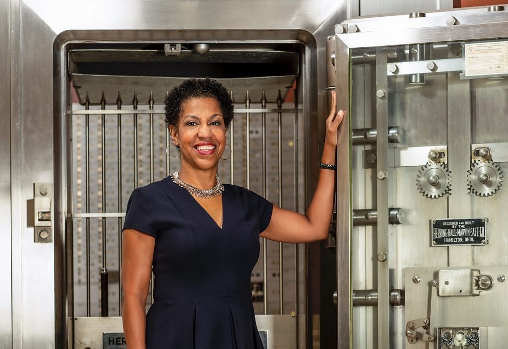 Image of Teri Williams standing in front of an open bank safe.